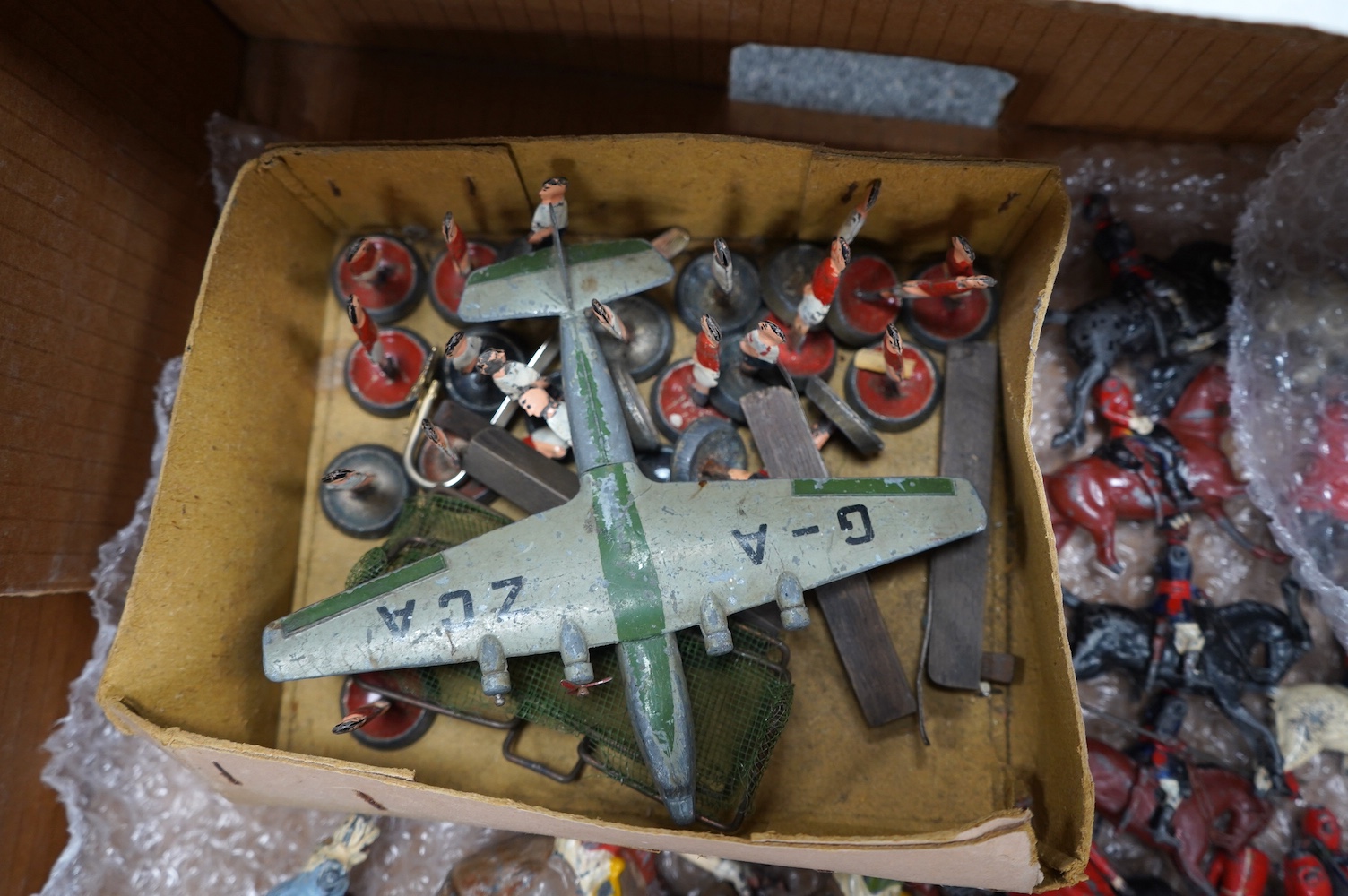 A collection of Britain's lead soldiers, etc. including; guards, Arabs mounted on camels, lancers, etc. together with a Dinky Toys airliner and early tinplate table football figures. Condition - poor, for restoration, mo